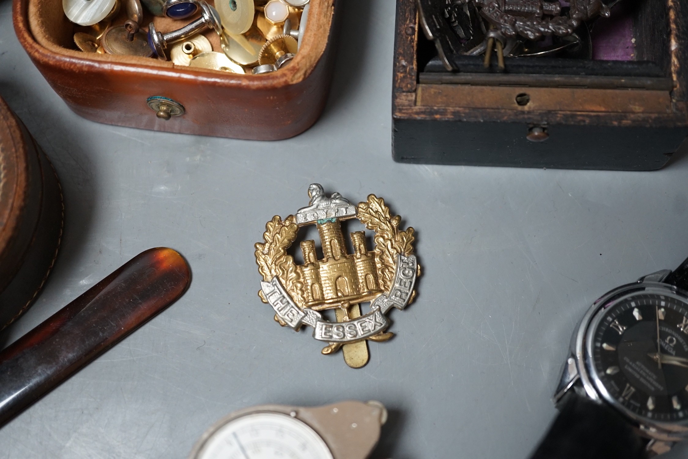 A collection of military cap badges, studs, camera, watch, etc